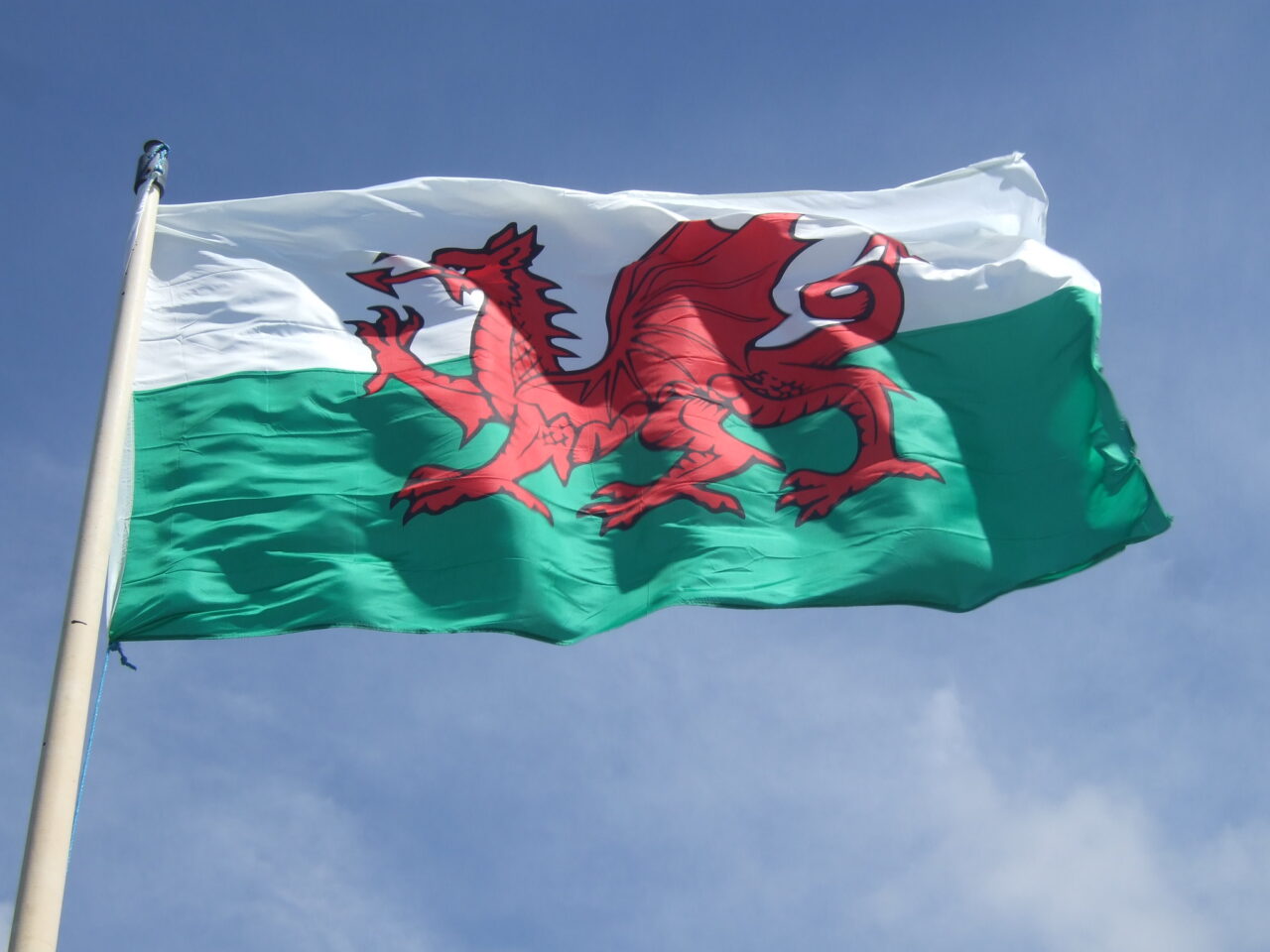 Baner Cymru yn chwifio ar fast. A Wales flag flying on a mast.