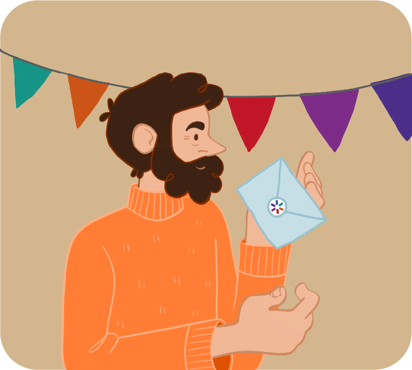 A bearded man in an orange jumper holds an envelope in his hand, with colourful bunting hanging behind him. | Mae dyn barfog mewn siwmper oren yn dal amlen yn ei law, gyda baneri lliwgar yn hongian y tu ôl iddo.